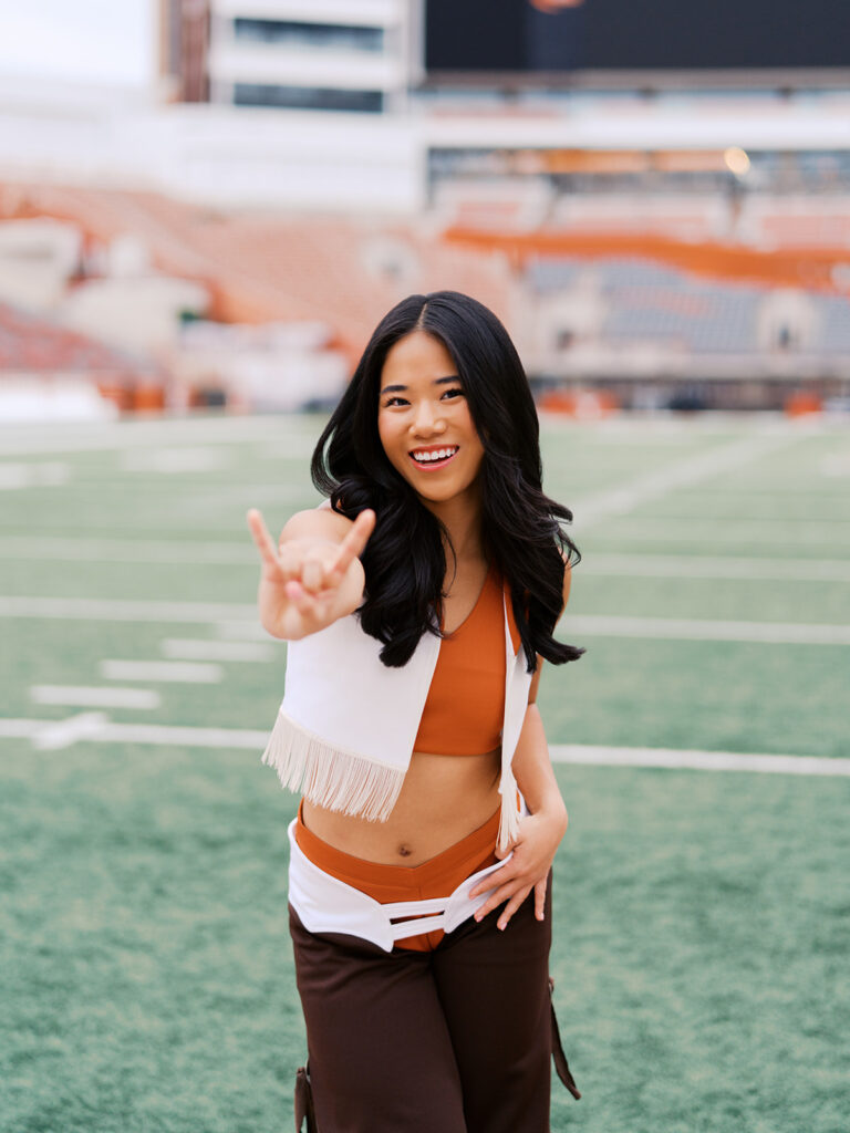 UT grad portraits at DKR Stadium with Texas Pom dancer on the field