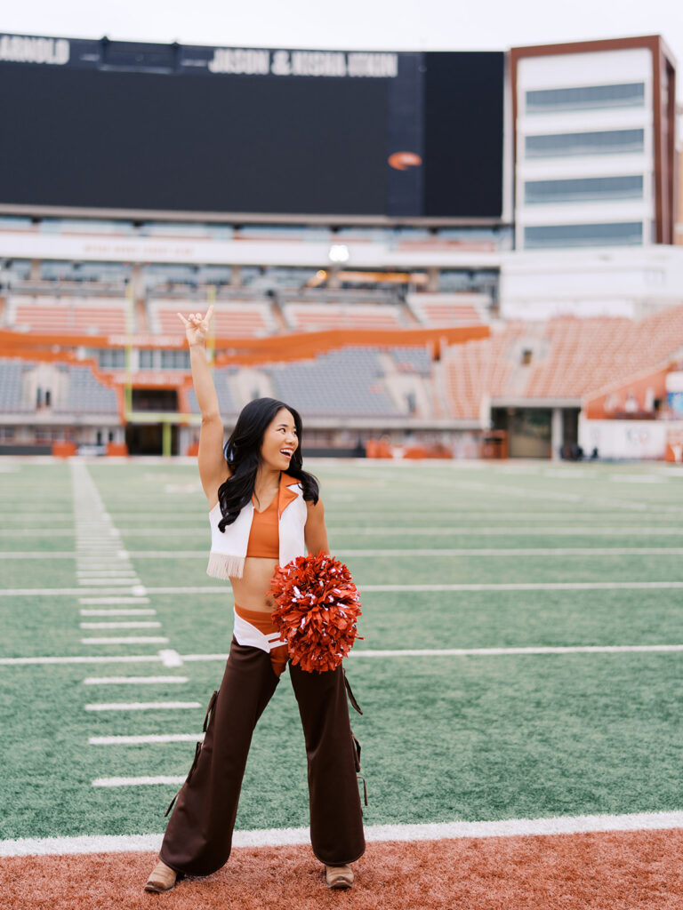 UT grad portraits at DKR Stadium with Texas Pom dancer on the field