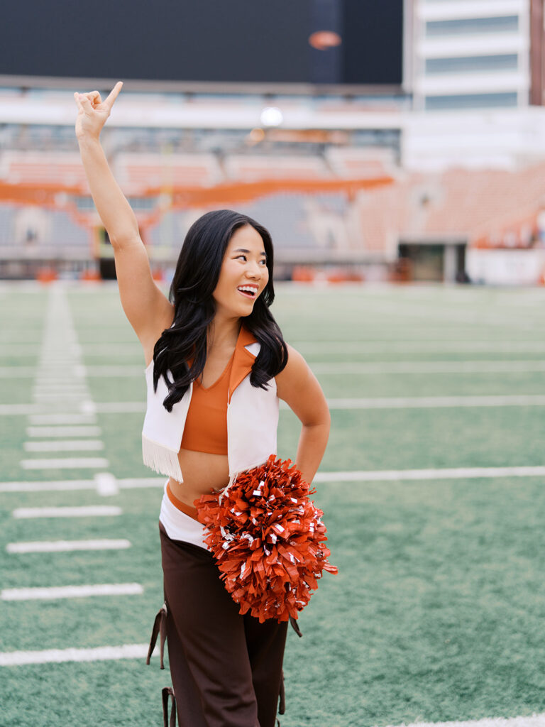 UT grad portraits at DKR Stadium with Texas Pom dancer on the field