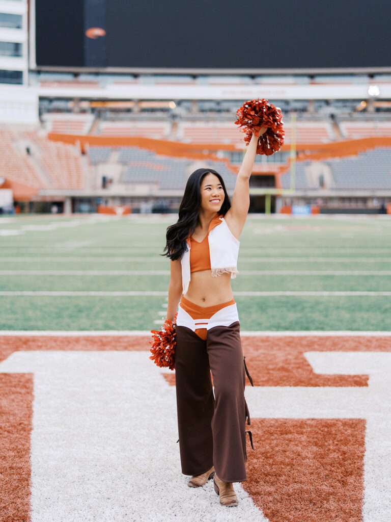 UT grad portraits at DKR Stadium with Texas Pom dancer on the field