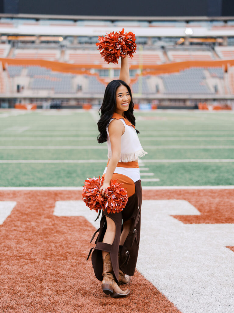 UT grad portraits at DKR Stadium with Texas Pom dancer on the field