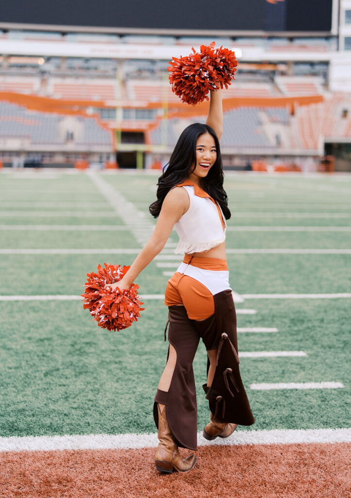 UT grad portraits at DKR Stadium with Texas Pom dancer on the field