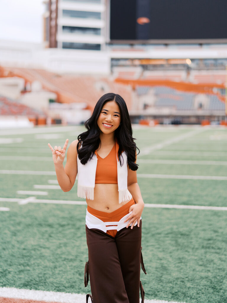 UT grad portraits at DKR Stadium with Texas Pom dancer on the field