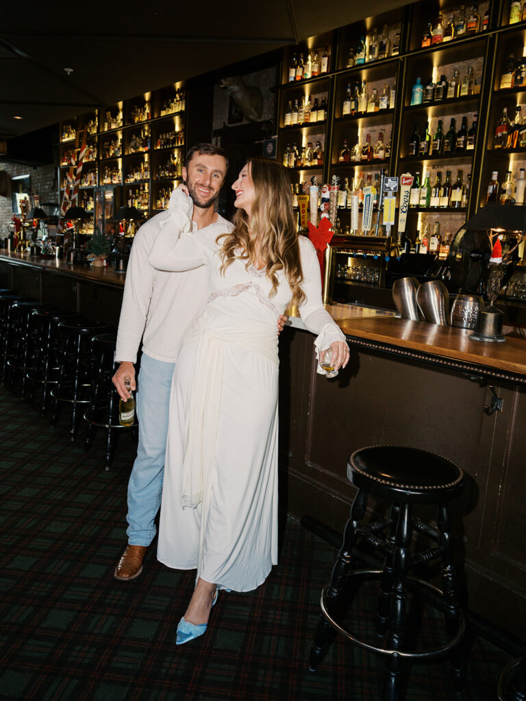 Chris and Reagan laughing at the bar during their Seven Grand Austin engagement session