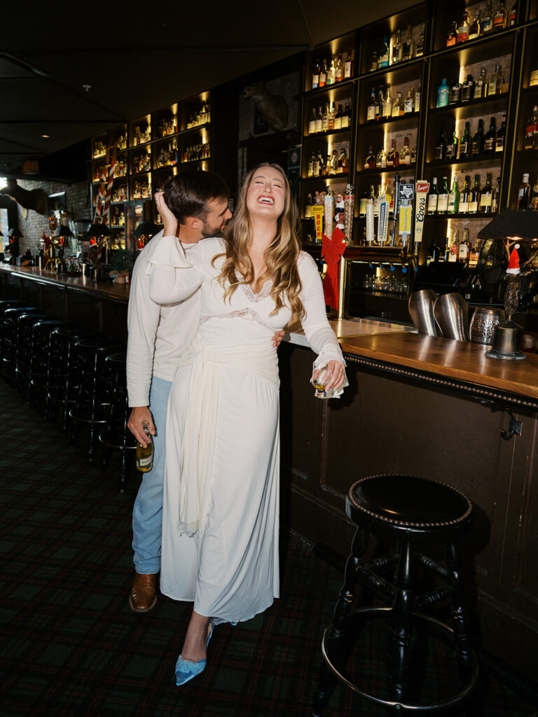 Chris and Reagan laughing at the bar during their Seven Grand Austin engagement session