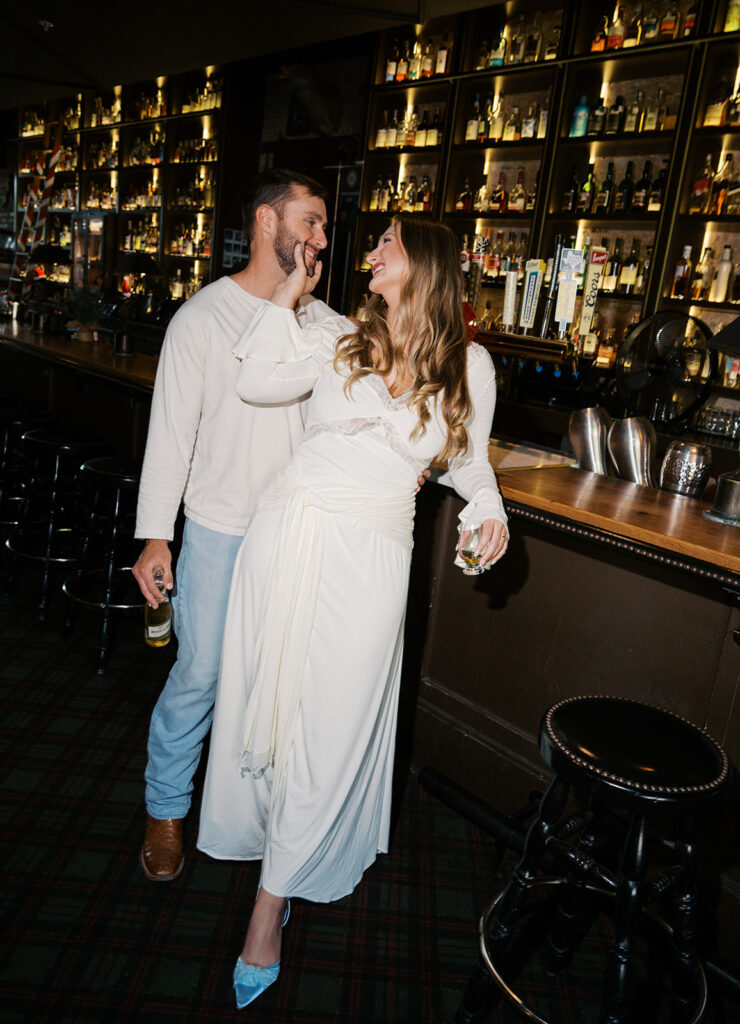 Chris and Reagan laughing at the bar during their Seven Grand Austin engagement session